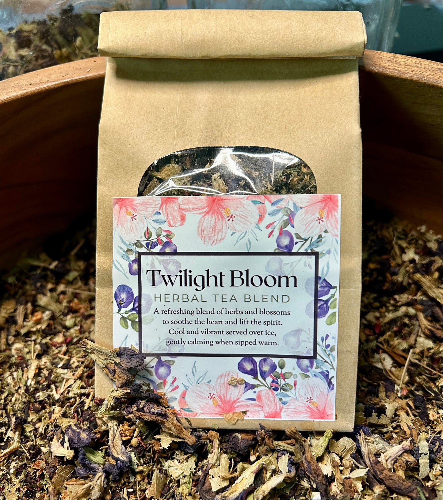 Tea bag labeled 'Twilight Bloom Herbal Tea Blend' surrounded by loose tea leaves.